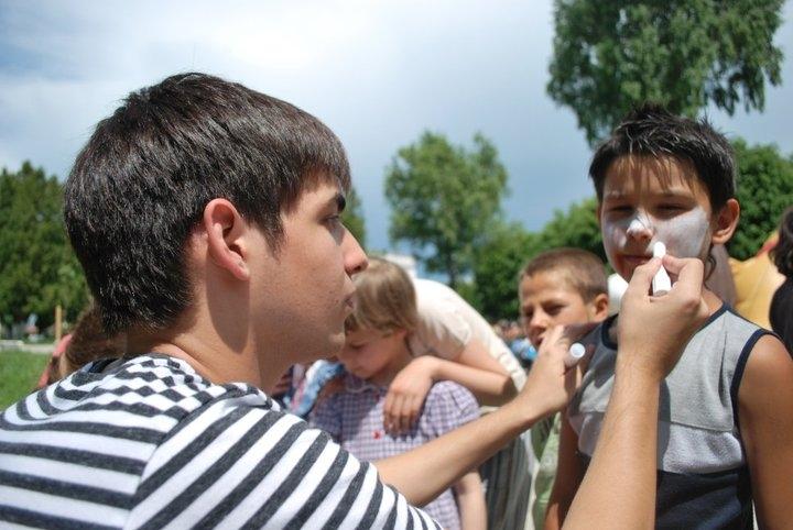 A Projects Abroad Childcare volunteer paints a child's face during day acivites outside a school in Romania. Projects Abroad volunteer with children in Romania paints a child's face during an outdoor activity at a Childcare placement.